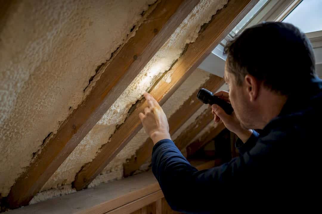 Surveyor examining uneven spray foam defects