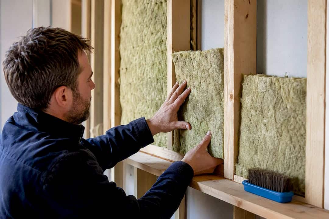 Installer fitting insulation between timber studs